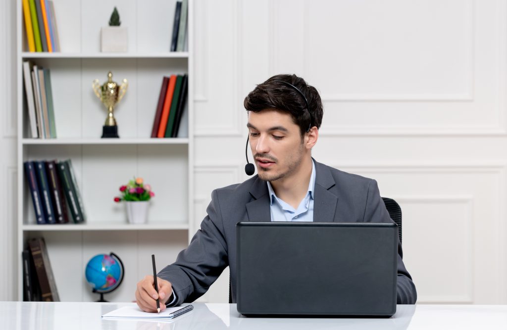 customer-service-handsome-man-grey-suit-with-computer-headset-taking-down-notes customer service handsome man grey suit with computer headset taking down notes